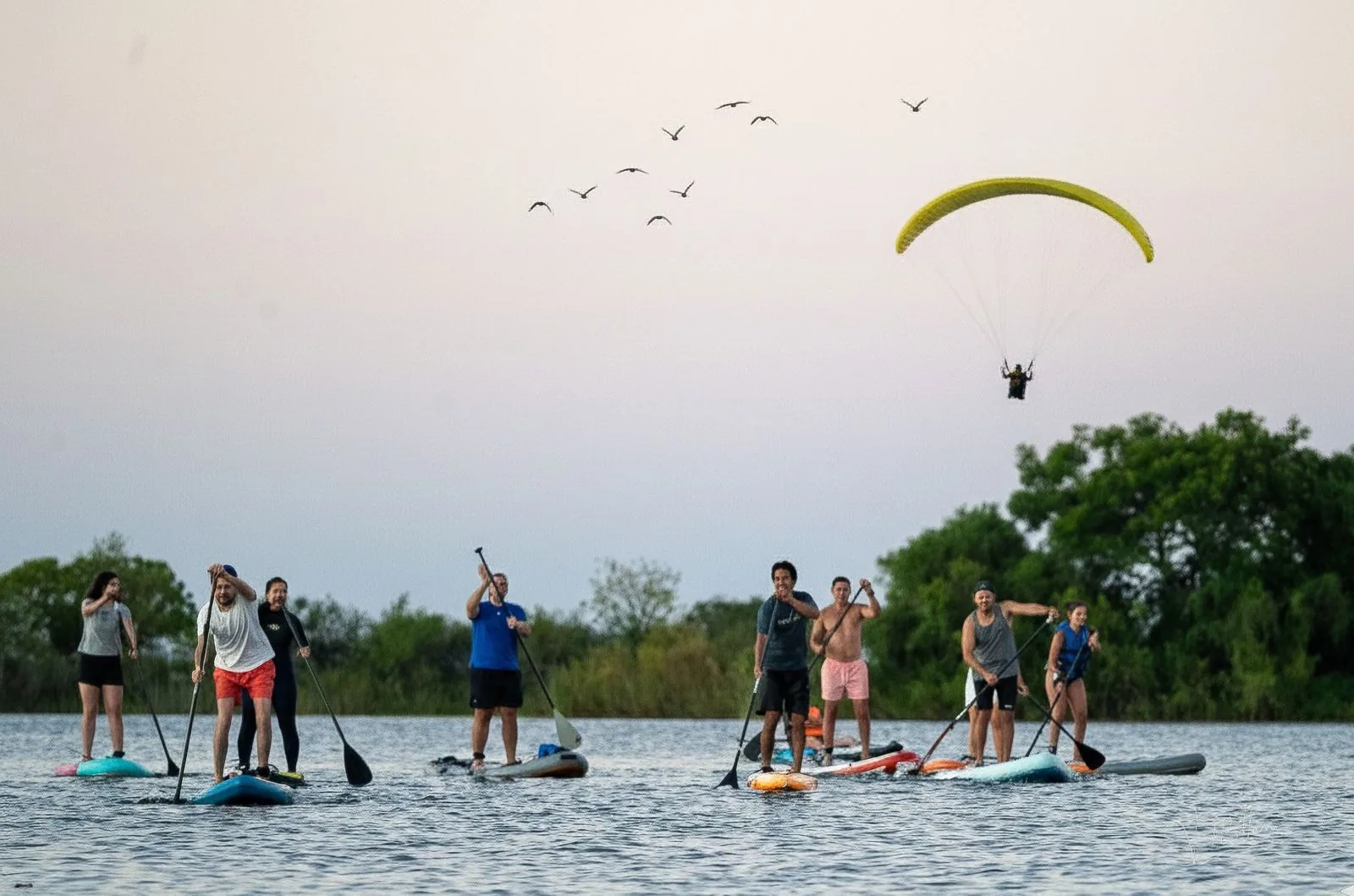 Paddleboarders on the lake at Salto Grande with a paraglider overhead