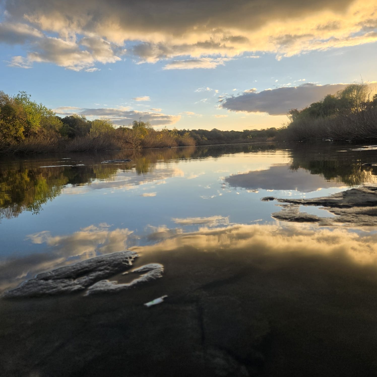 Sunset clouds mirrored in the still Río Daymán at Termas del Daymán, Salto, Uruguay