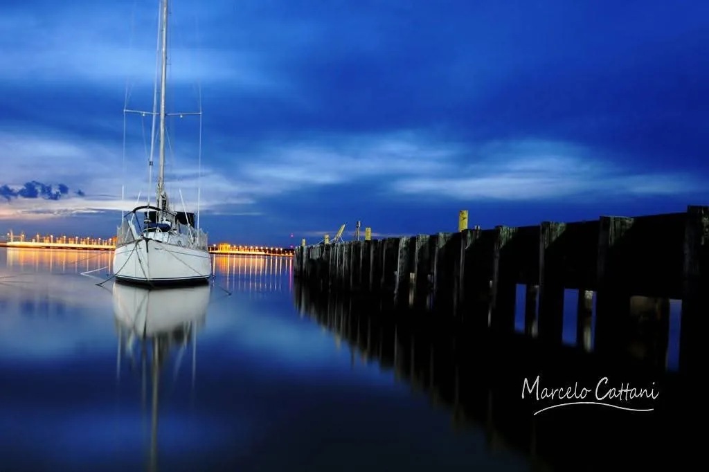 A sailing boat moored at a pier on the Río Uruguay at blue hour
