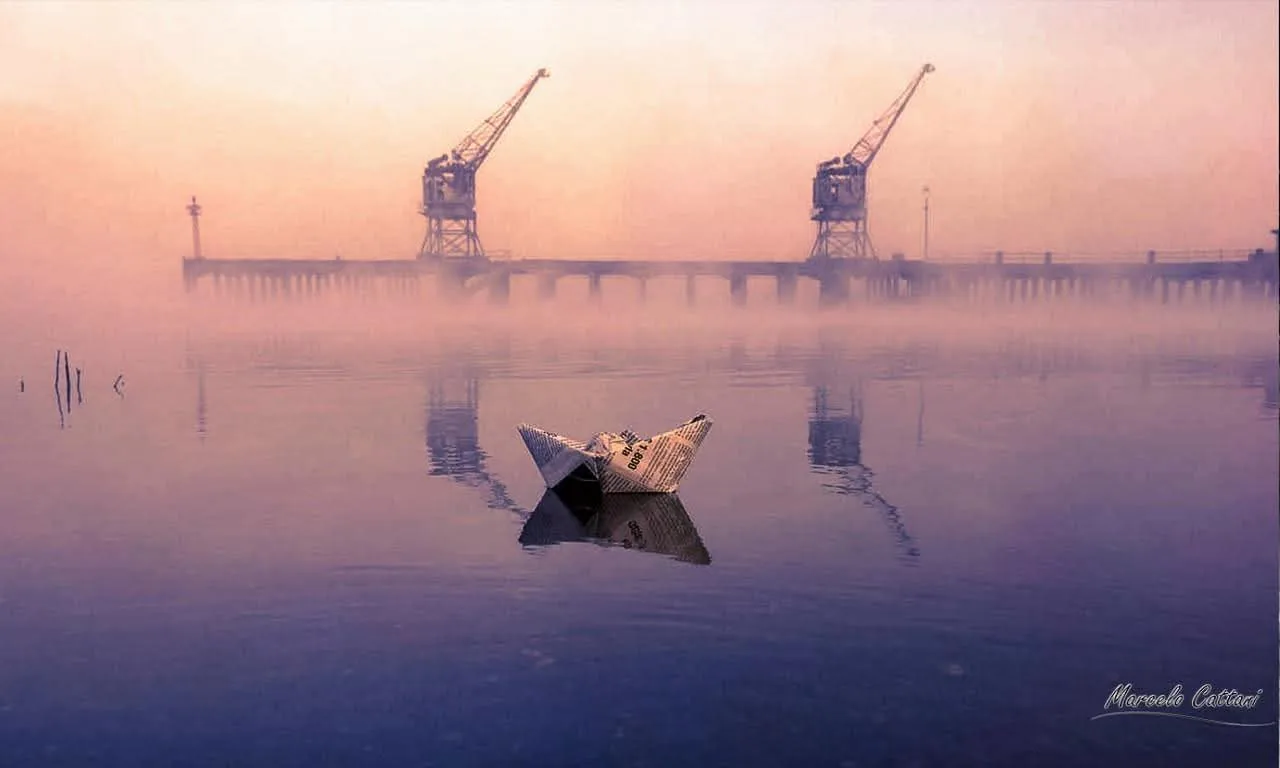 Port cranes of Salto in morning fog, a fisherman in a small boat on the river