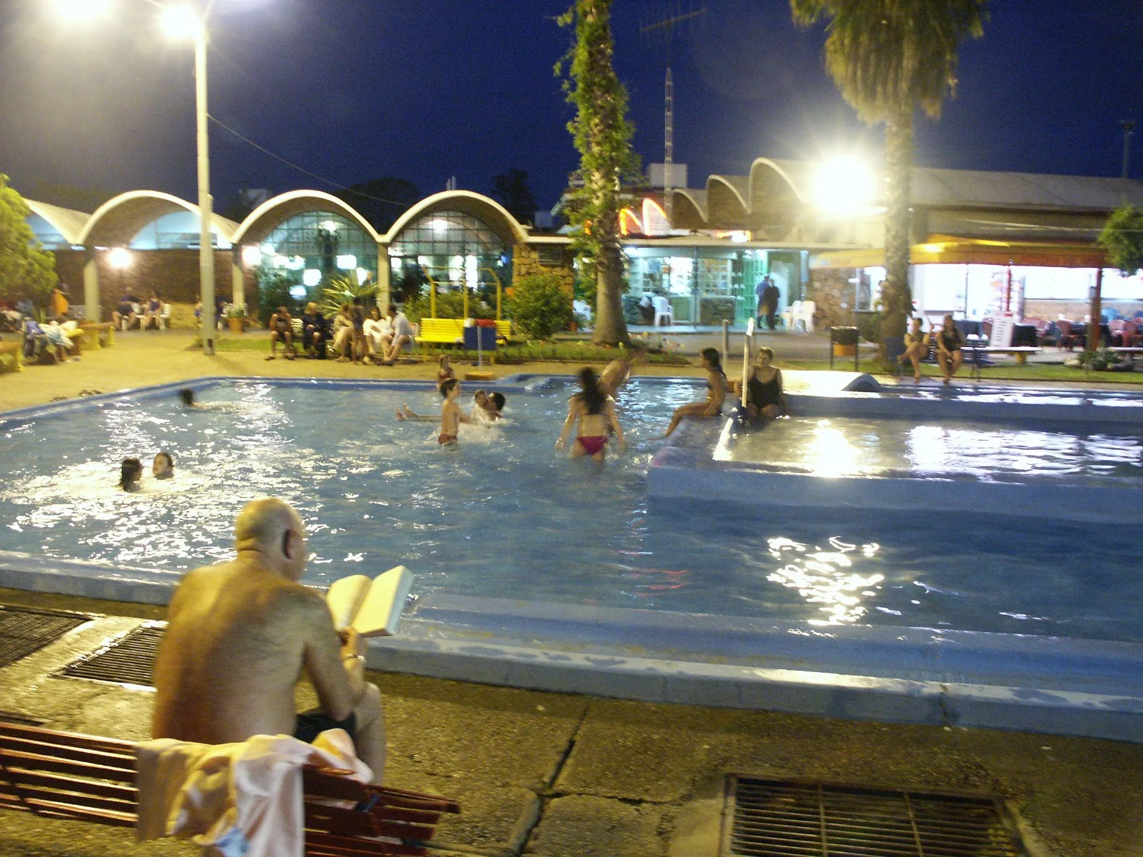 A man reading beside the thermal pool at night at Termas del Daymán, Salto