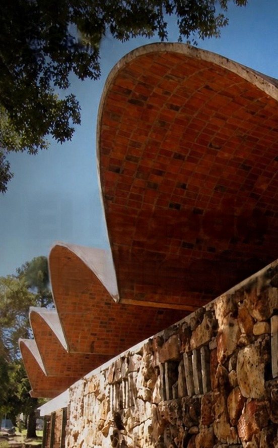 Self-supporting brick vaults by Eladio Dieste rising over a stone wall in Salto