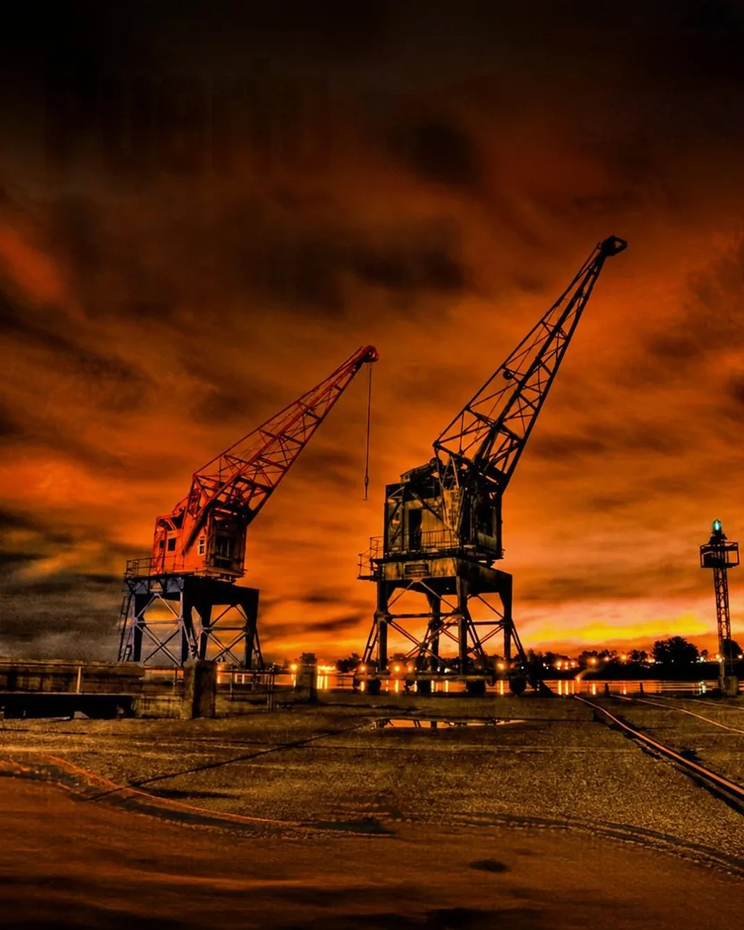 The old cranes of the port of Salto against a fiery sunset over the Uruguay River